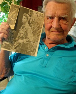 Villager Bill MacNeill holds a photo of himself as a young solder in World War II.