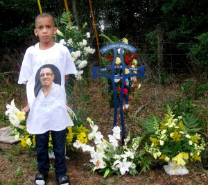 Justice Powell  wears a T-shirt bearing the image of his uncle, Cole Powell at a makeshift memorial on County Road 466A. 