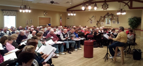 Villager Bill Davis, at right in brown shirt, leads the new Villages choral group in its first rehearsal. 