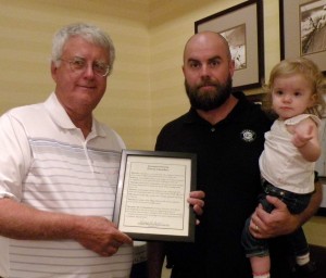 Rich St. Andre, president of the Mission Hills Neighborhood Club presents David Chambers with a certificate of appreciation. Chambers is holding Cora, the youngest of his three daughters.