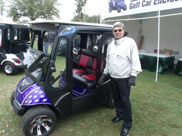 Sleekline Golf Car Enclosures representative Bob Schultz standing next to a cart outfitted with the company's new, weather-tight golf car enclosure