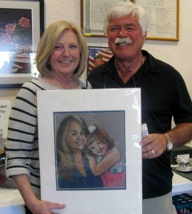 Bennie and Tom Harter with a portrait sketched by Villager of Roz Fox. The portrait is of their granddaughter and her mother.