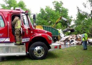 Personnel at the transfer station on Rolling Acres Road clean up after trash caught on fire in the rear of a truck.