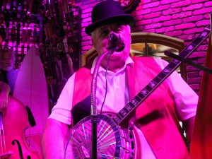 Gary Crawley is bathed in a purple stage light as he sings and plays banjo at World of Beer.   