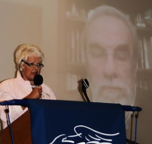 Villages Tea Party President Aileen Milton with an image of speaker Michael Cutler in the background.