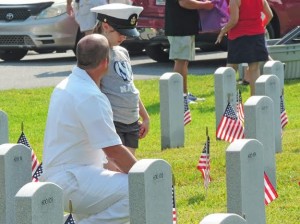 A soldier from Brooksville explains to his daughter the importance of placing flags at grave sites. (Ron Clark photo)