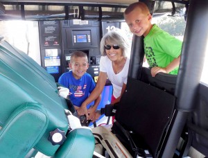 Villager Eleanor Barnard fills her golf cart with gas with help from grandsons Jack, left, and Logan. 