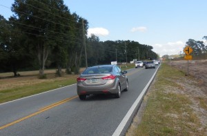 Cars travel on County Road 466A near the intersection with Micro Racetrack Road. 