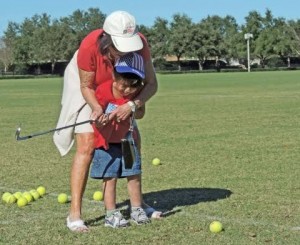 Elizabeth Baltazar, 5, is coached on hitting a golf ball by Lyndia Merriweather of the Village of Liberty Park. (Ron Clark photo)