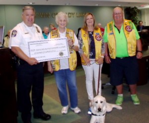 Police Chief Chris McKinstry accepts a $1,500 donation from Orange Blossom Gardens Lions Club members Doris Turlo, Linda Little and John Buswell, from left.