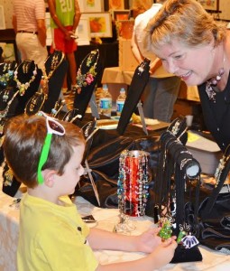 Aidan Sullivan, 6, chose a Christmas necklace at Janet Gardiner's hand-made jewelry display. ​