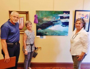 Show judge, Rich Woy, poses with Billie Edwards' first place acrylic, 'Italian Water Garden,' inspired by Claude Monet. At right is the exhibit chair, Catherine Sullivan.