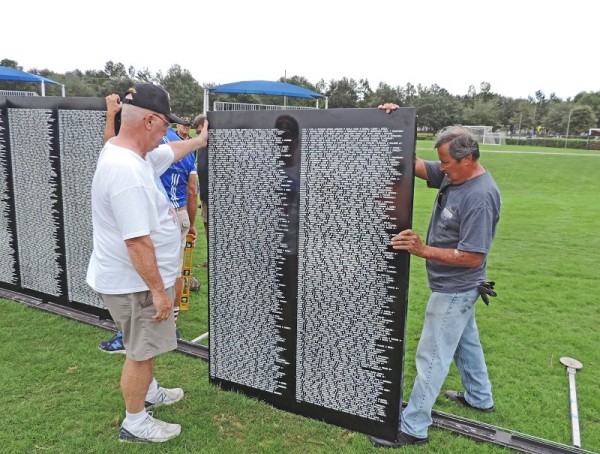 Gary Woodruff, left, helps set up a section of the Traveling Vietnam Memorial Wall. 