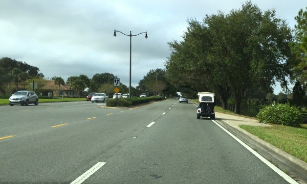 A golf cart made a right turn onto County Road 466 from the Morse Gate. 