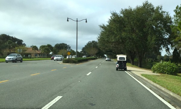 A golf cart heads down County Road 466.