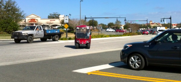 A misguided golf cart goes through a busy intersection on County Road 466.
