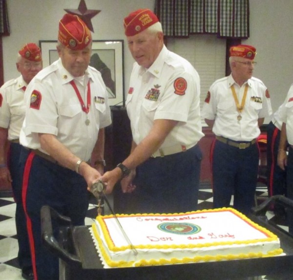 Donald Westlake and Ernest Cooper cut the cake with a sword.