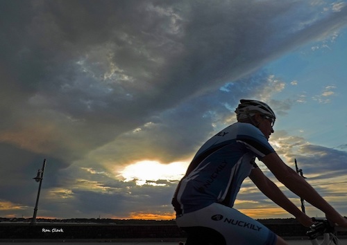 A bicyclist crosses the Morse Bridge at sunrise