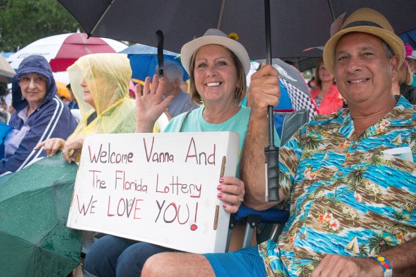 Sherry and Rick Adamson huddle under an umbrella in their front row seats waiting for the appearance of Vanna White. The couple moved into the Village of LaBelle North just a month ago. Photo by Tom Burton.