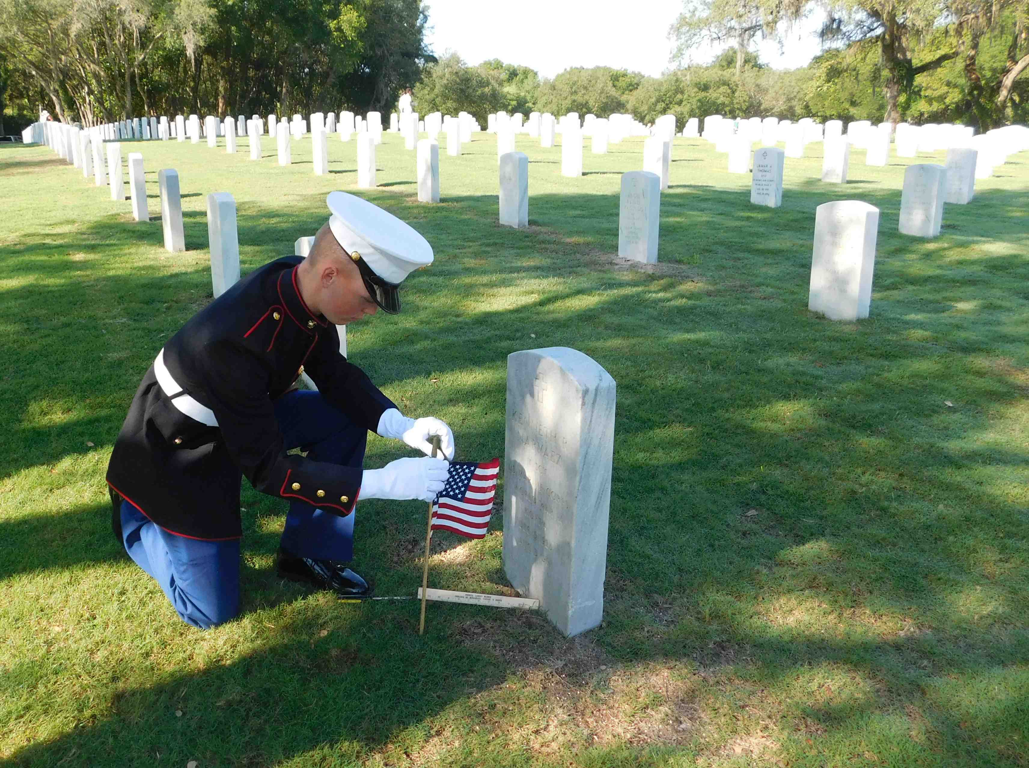 Pvt. Caleb Flaville placing flag at grave of fellow Marine, Kenneth Narvaez.