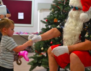 Santa Claus offers a gift to a 2-year-old at Saturday's event.
