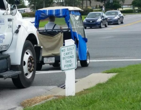 The driver of this golf cart ignores a sign that said, "No Golf Carts Beyond This Point."