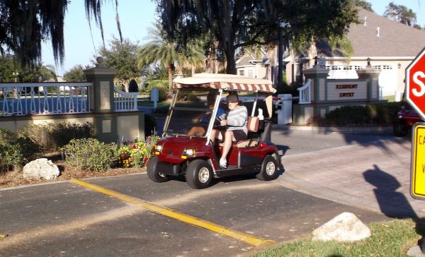 A golf cart approaches a speed bump near the entrance to the Village of Bridgeport at Lake Sumter. 