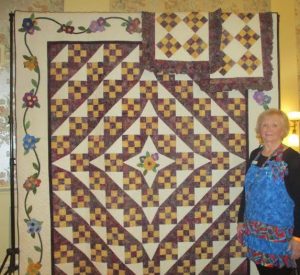 Judy Porter, chairman of the Quilt Show, standing with the quilt that is being raffled off to benefit Hospice House of the Villages and Honor Flight. The quilt is valued at over $3,000.