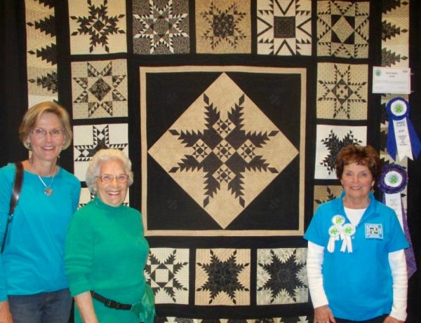 Quilt enthusiasts Darlene Clark and Anna Field with Audrey Temmer and her winning quilt.