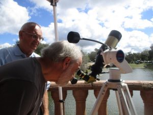 David Kolbe, assisted by Astronomy Club member Jerry Kosarko, looks at the sun through a telescope that filters 99.9 percent of solar rays making it safe to view.