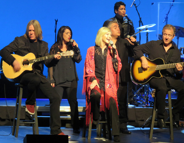 Olivia Newton-John and her band on stage.