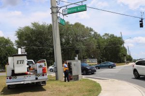 A technician adjusts traffic lights at the intersection of County Road 466 and Rolling Acres Road.
