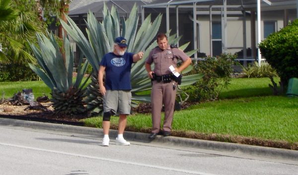 A Florida Highway Patrol investigator on Friday talks to a witness at the scene of an accident that claimed the life of a man in a golf cart