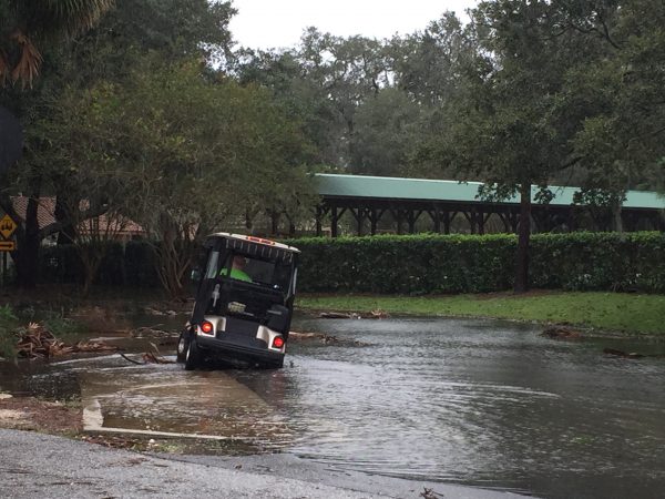 Man attempting to drive on golf cart bridge over U.S. Hwy 441. Both sides of the bridge are flooded. 