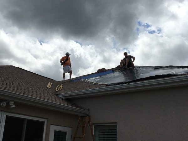 Neighbors putting up tarps to cover roof damage