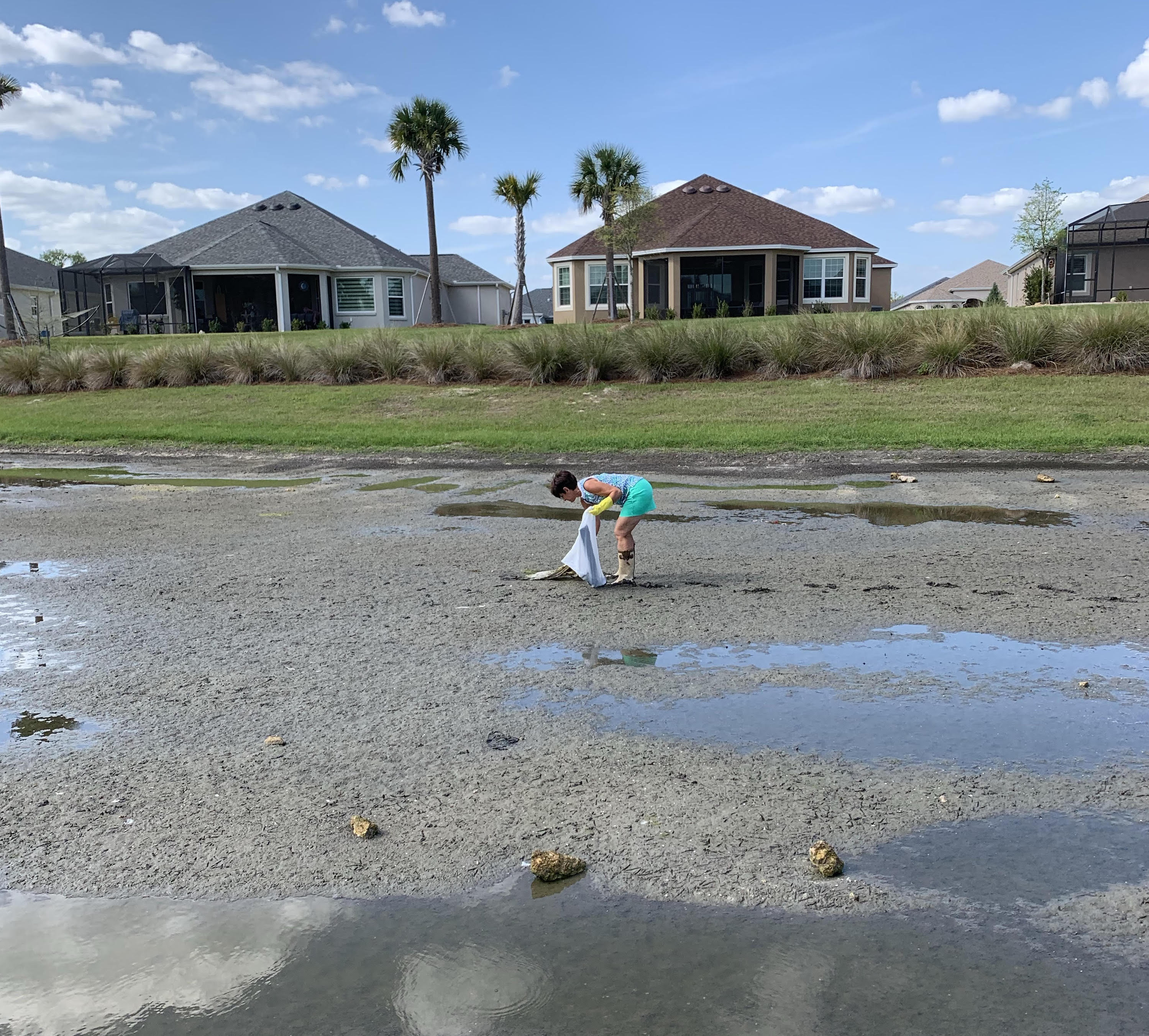 villager picks up debris in dry pond after buildout in village