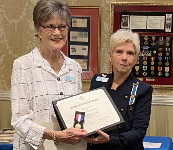 Nathalie Heydet left was presented with a pin and award by John Bartram Regent Cindy Kolevar.