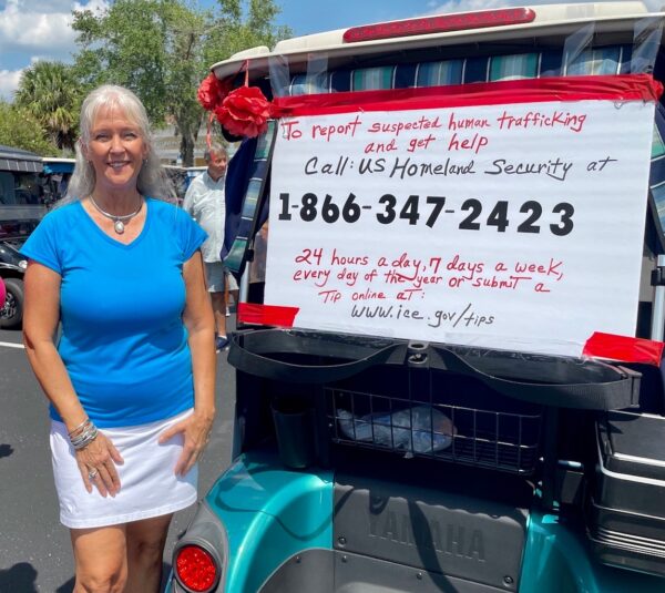 Celine Goins stands with her golf cart decorated with the number for Homeland Security