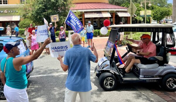 Supporters of both Donald Trump and Kamala Harris waved signs during the golf cart rally