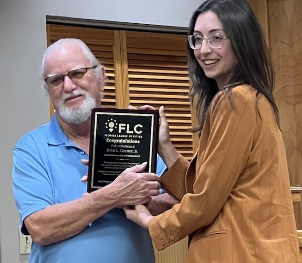 Eryn Russell of the Florida League of Cities presents an award to Commissioner John L.Gunter for his 31 years on the Fruitland Park Commission.